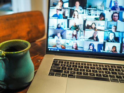 A computer on a table showing a video call conference.